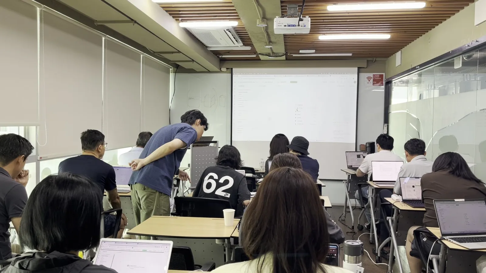 강사가 수강생 자리에서 노트북 화면을 함께 보며 문제를 해결하는 모습